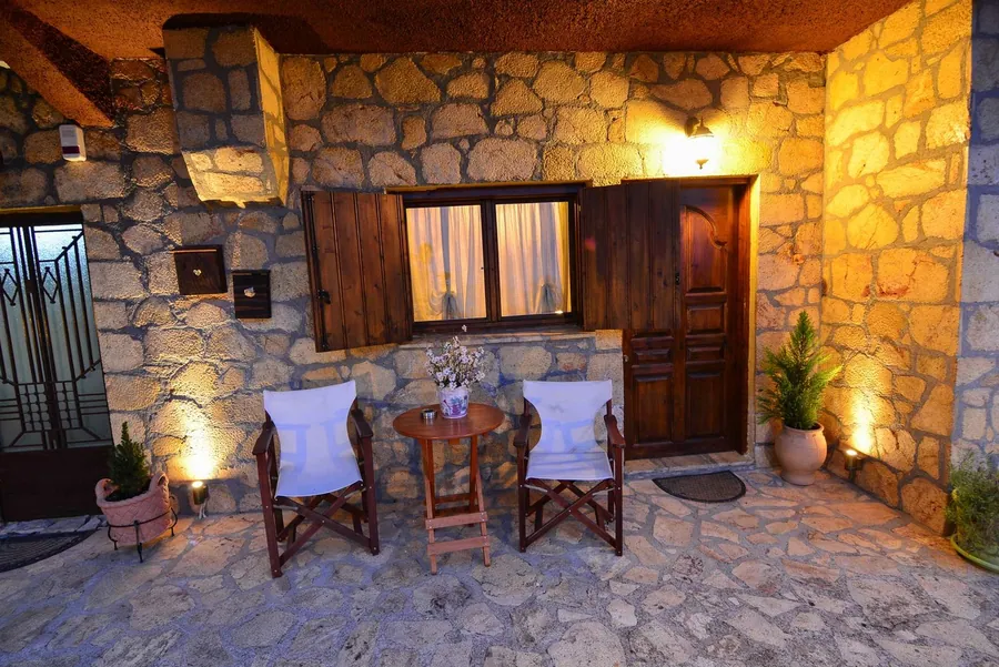 Πέτρινη βεράντα με ξύλινο τραπεζάκι, δύο καρέκλες και φανάρια